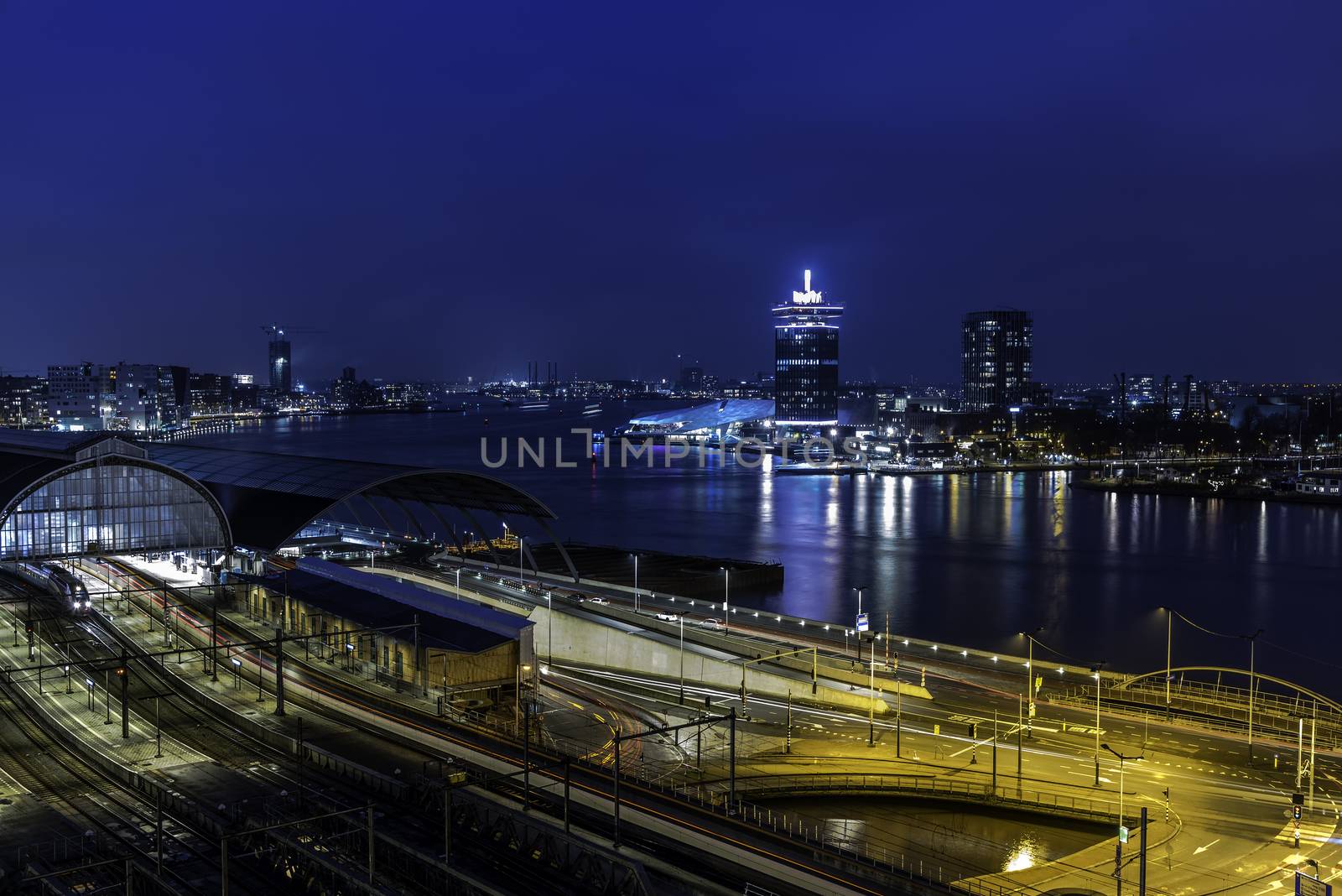 View of the Amsterdam train station and the Amstel river at night, Netherlands