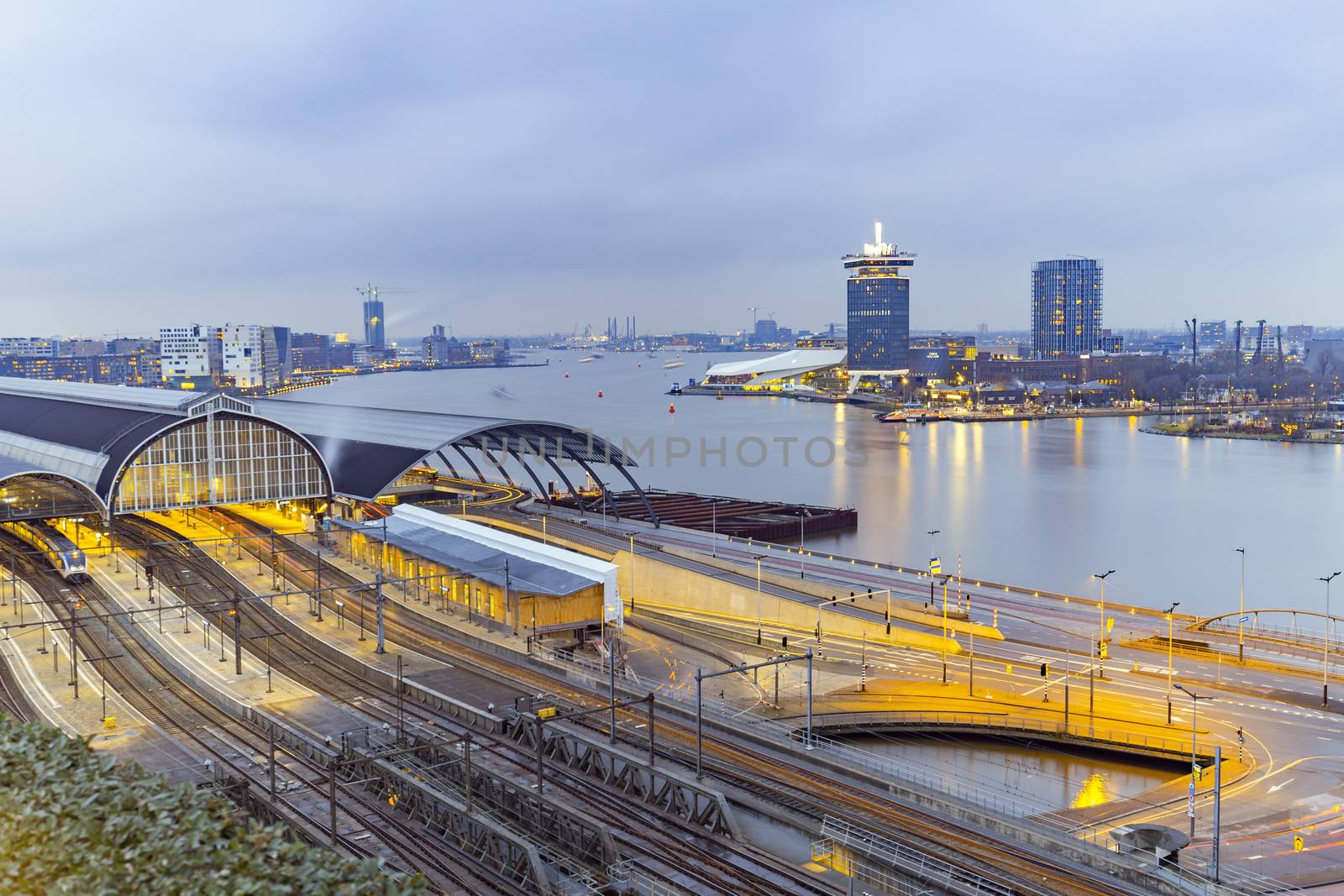 Amsterdam train station and the Amstel river at night by ankorlight