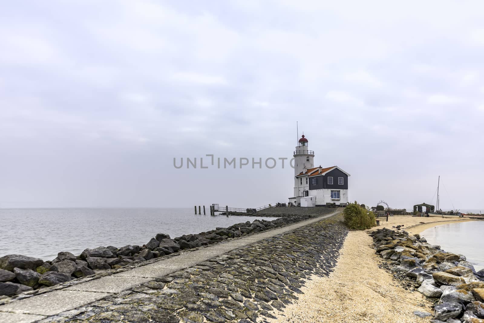 View of the white Marken island lighthouse under a foggy and cold skyline in the early morning, Netherlands by ankorlight
