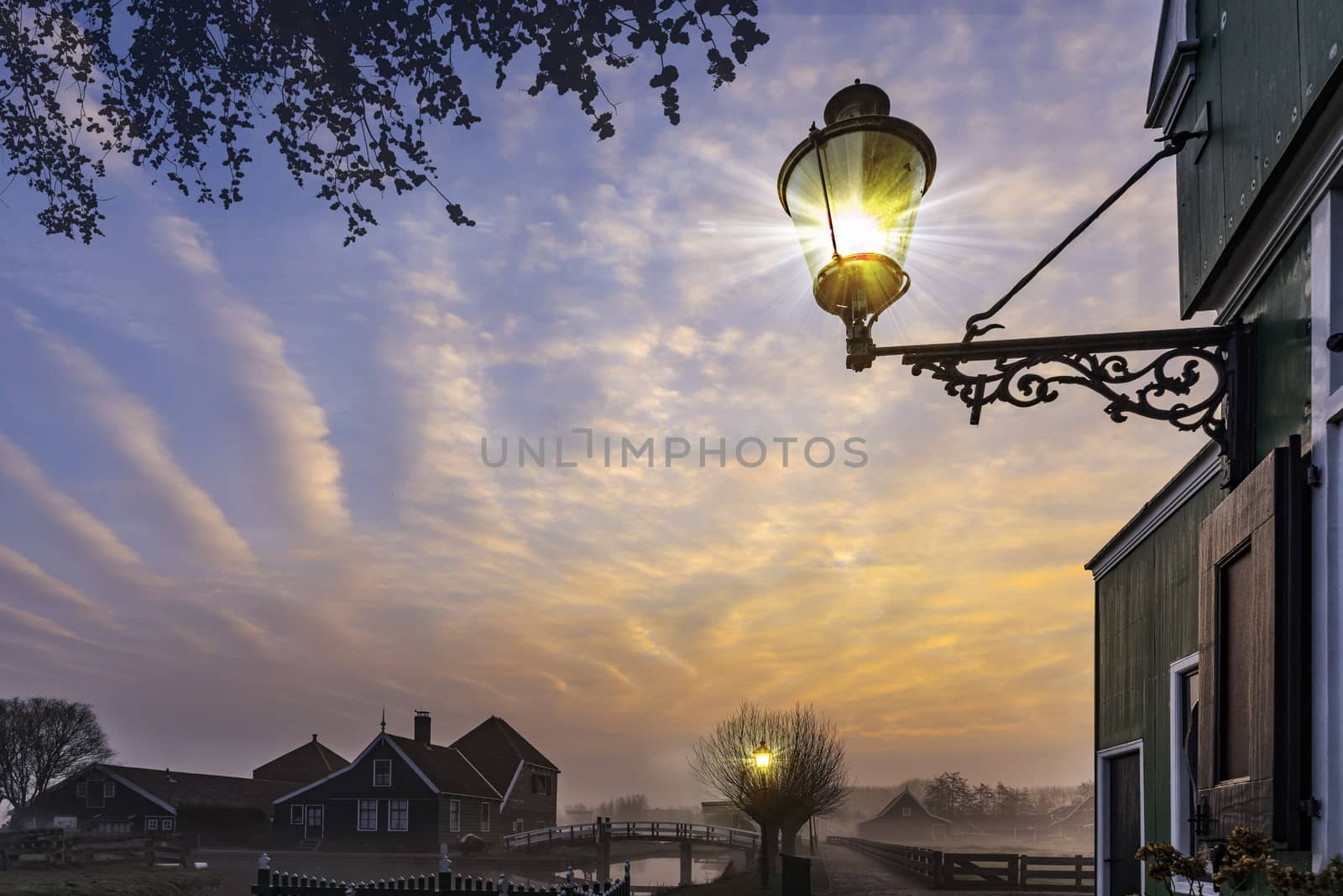 Hanging lamppost Beautiful typical Dutch wooden houses architecture at the sunrise moment mirrored on the calm canal of Zaanse Schans located in the North of Amsterdam, Netherlands