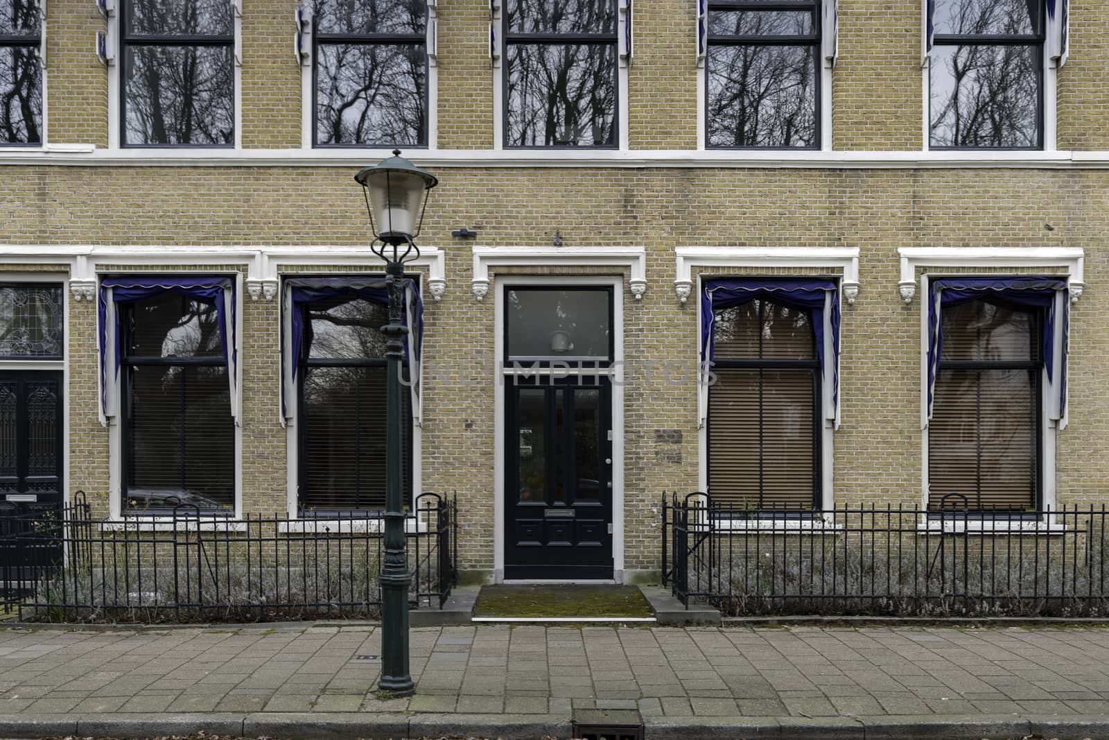 Victorian style wooden front door and windows along a main road and protected by concrete poles and flowers pots against car parking by ankorlight