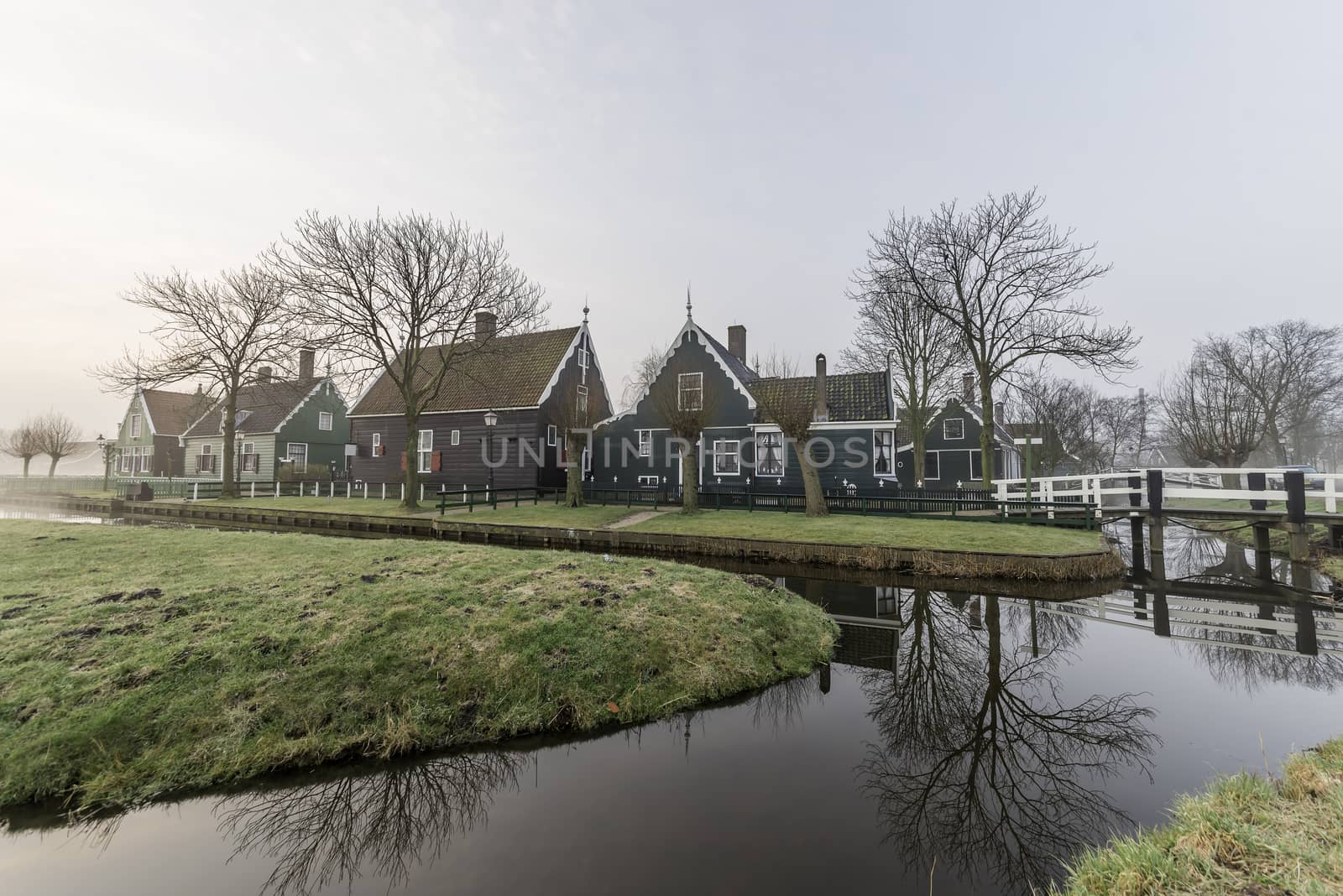 Beautiful typical Dutch wooden houses architecture mirrored on the calm canal of Zaanse Schans located at the North of Amsterdam, Netherlands by ankorlight