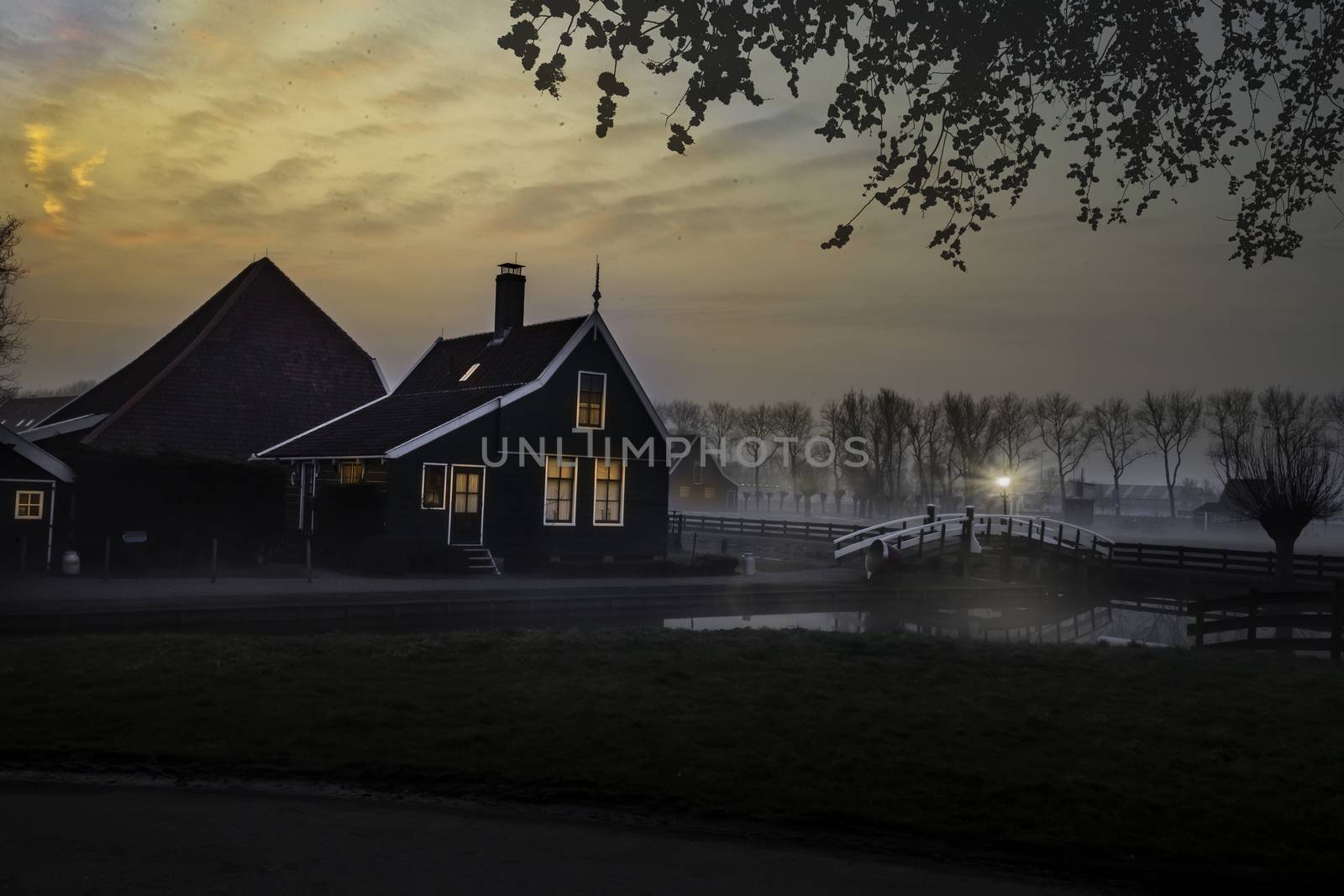 Ducks flying over a beautiful typical Dutch wooden houses architecture at the sunrise moment mirrored on the calm canal of Zaanse Schans located in the North of Amsterdam, Netherlands by ankorlight