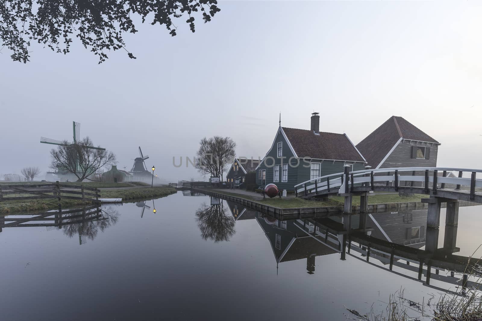 Beautiful typical Dutch wooden houses architecture mirrored on the calm canal of Zaanse Schans located at the North of Amsterdam, Netherlands