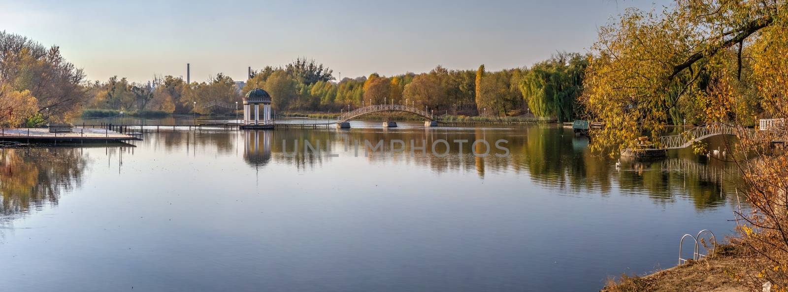 Sunny autumn evening on the blue lake with yellow trees. The Ivanki village in Cherkasy region, Ukraine