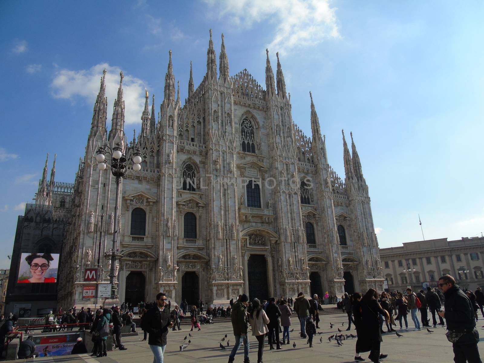 Milan, Italy - 02/01/2020: An amazing caption of the Duomo of Milan in winter days with some people enjoying the evening and beautiful coloured sky. Details of the old church from external part.