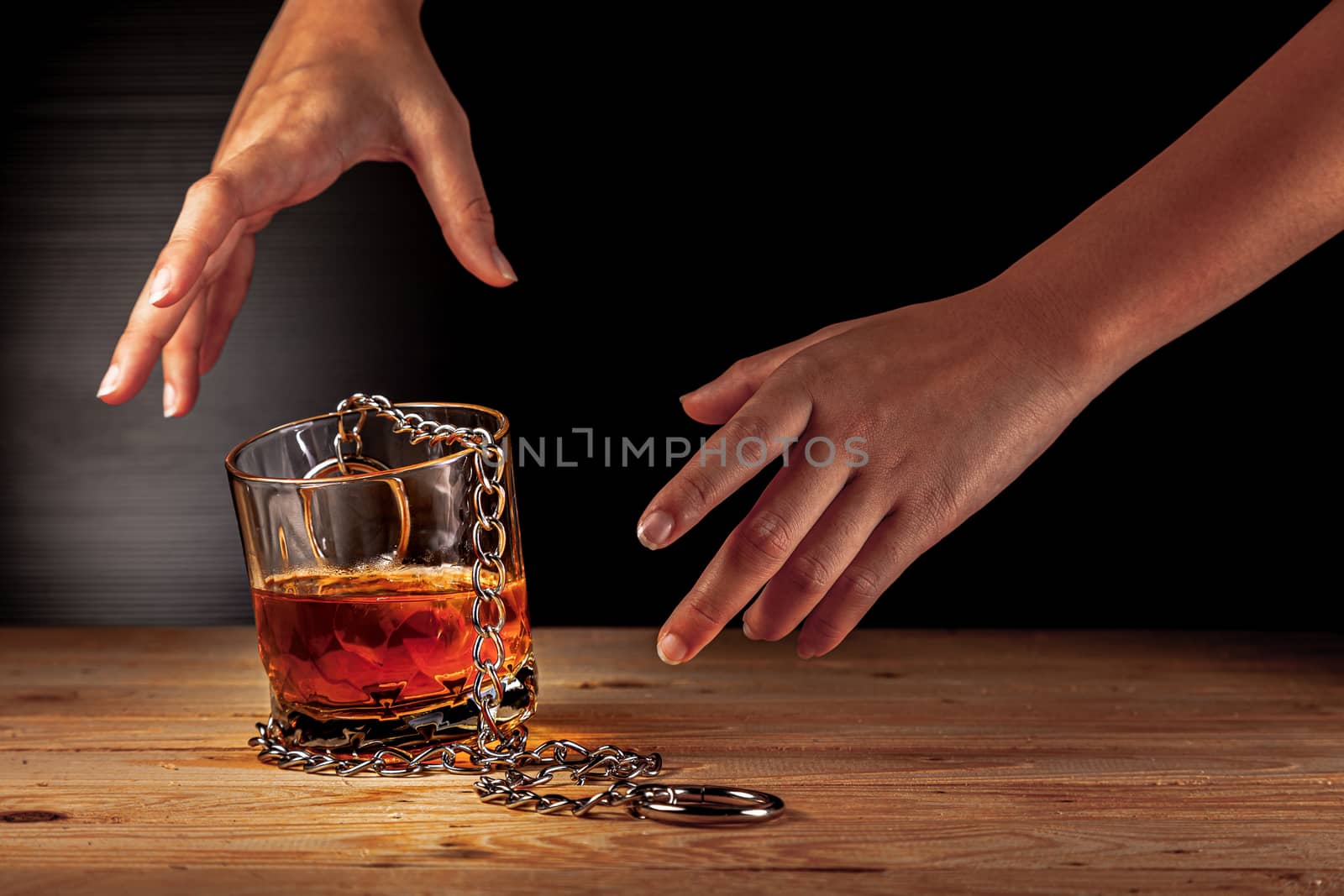 Alcoholism concept . Hands lock chain a glass of whiskey To stop drinking . Stop alcohol addiction . Addicting to alcoholic drink. 