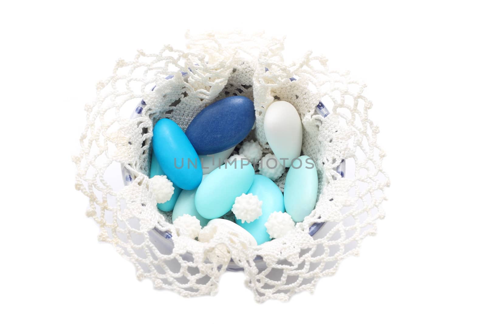 Blue and white sugared almonds in bowl covered with lace