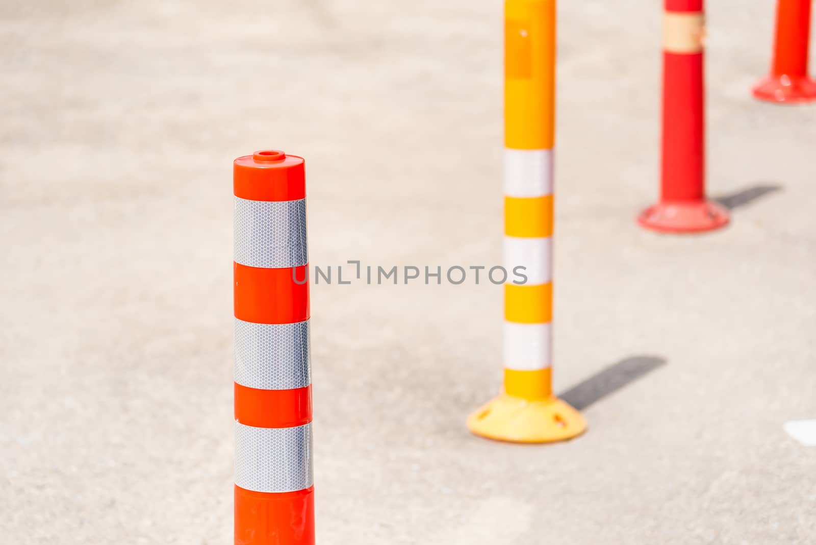 Bright orange traffic cones standing in a row on asphalt road. by Bubbers