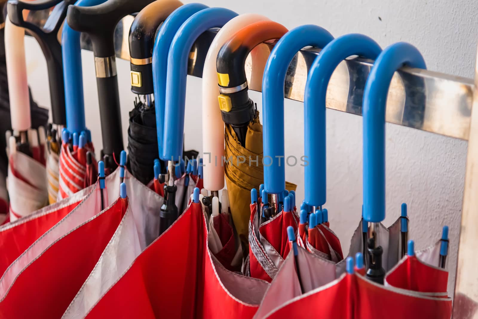 Red umbrellas hanging on the row.Many umbrellas hanging on white rail for people use.