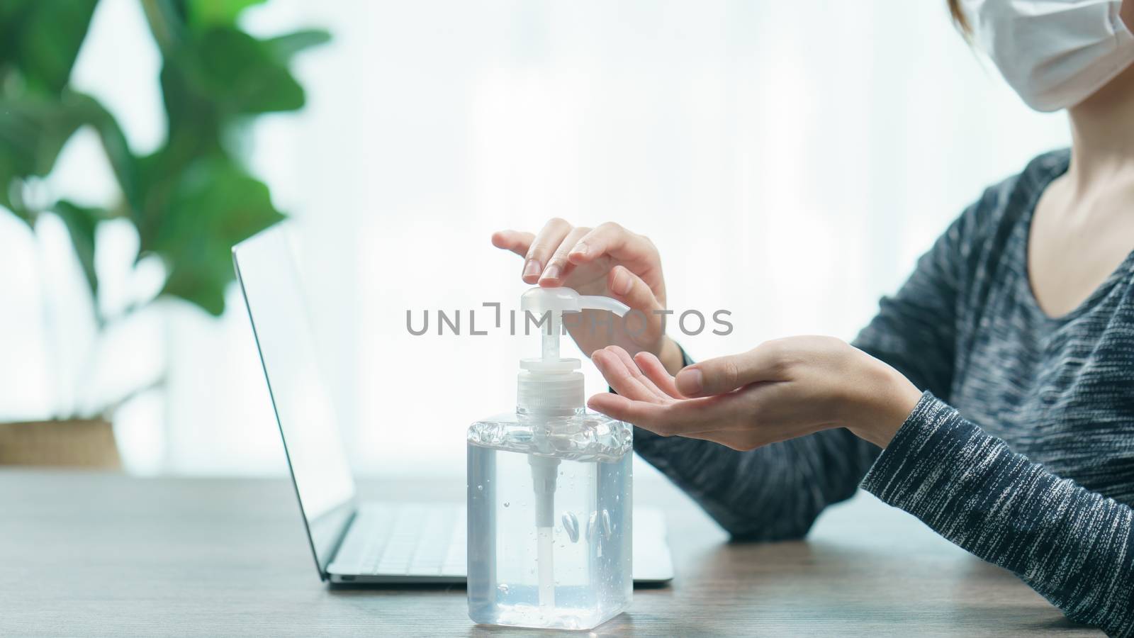 Woman worker wear protective face mask cleaning her hands with sanitizer liquid antibacterial gel, working from home in quarantine, corona virus concept.