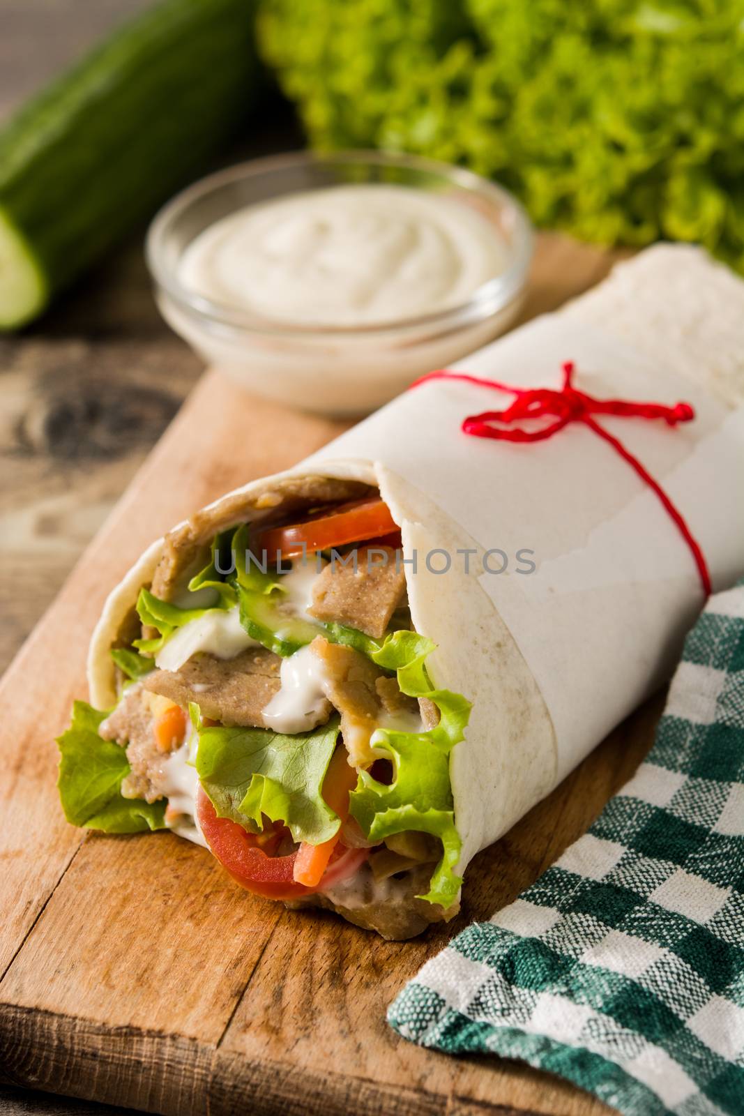 Doner kebab or shawarma sandwich on wooden table.