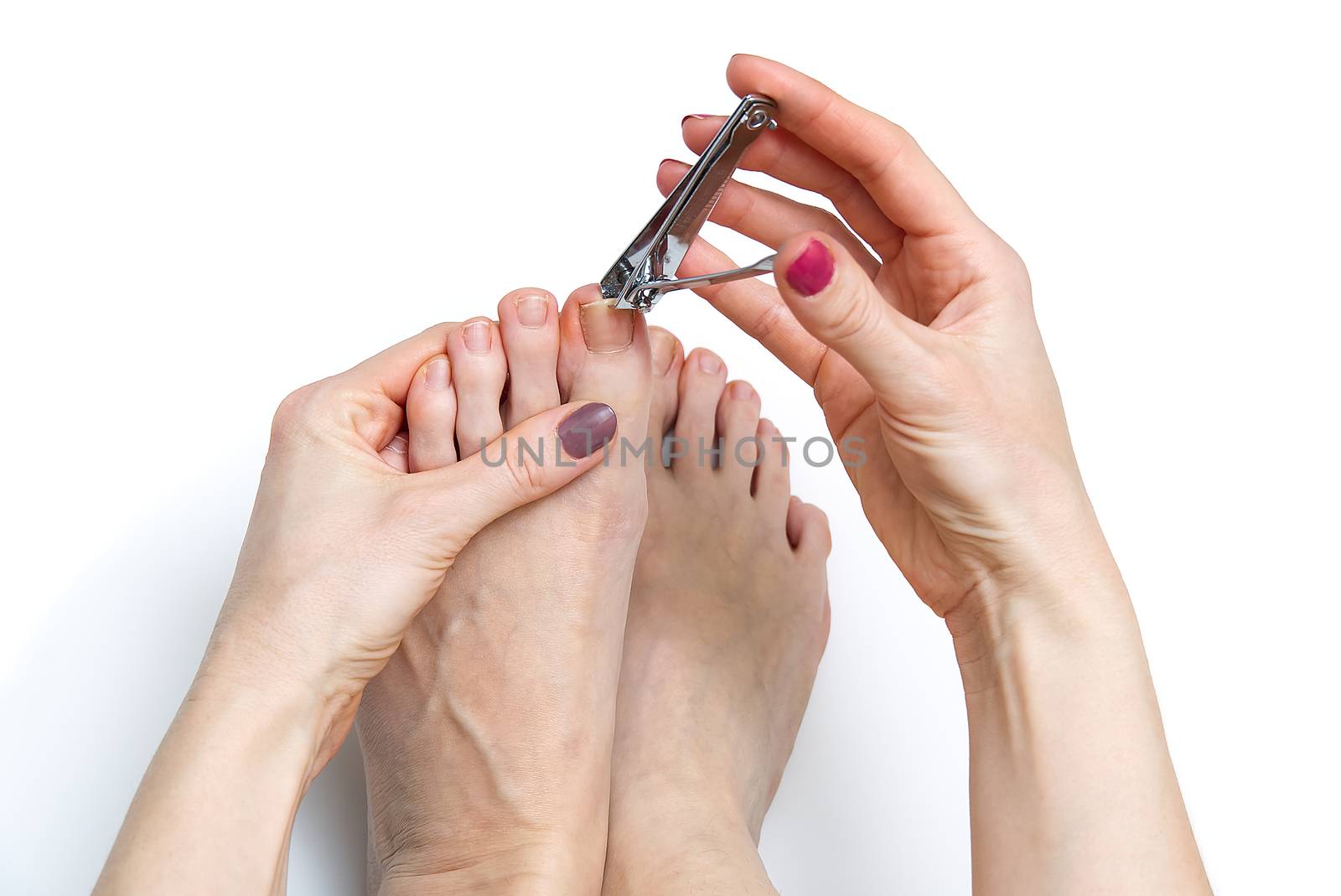 Woman at home spa doing pedicure to herself in white background, close-up