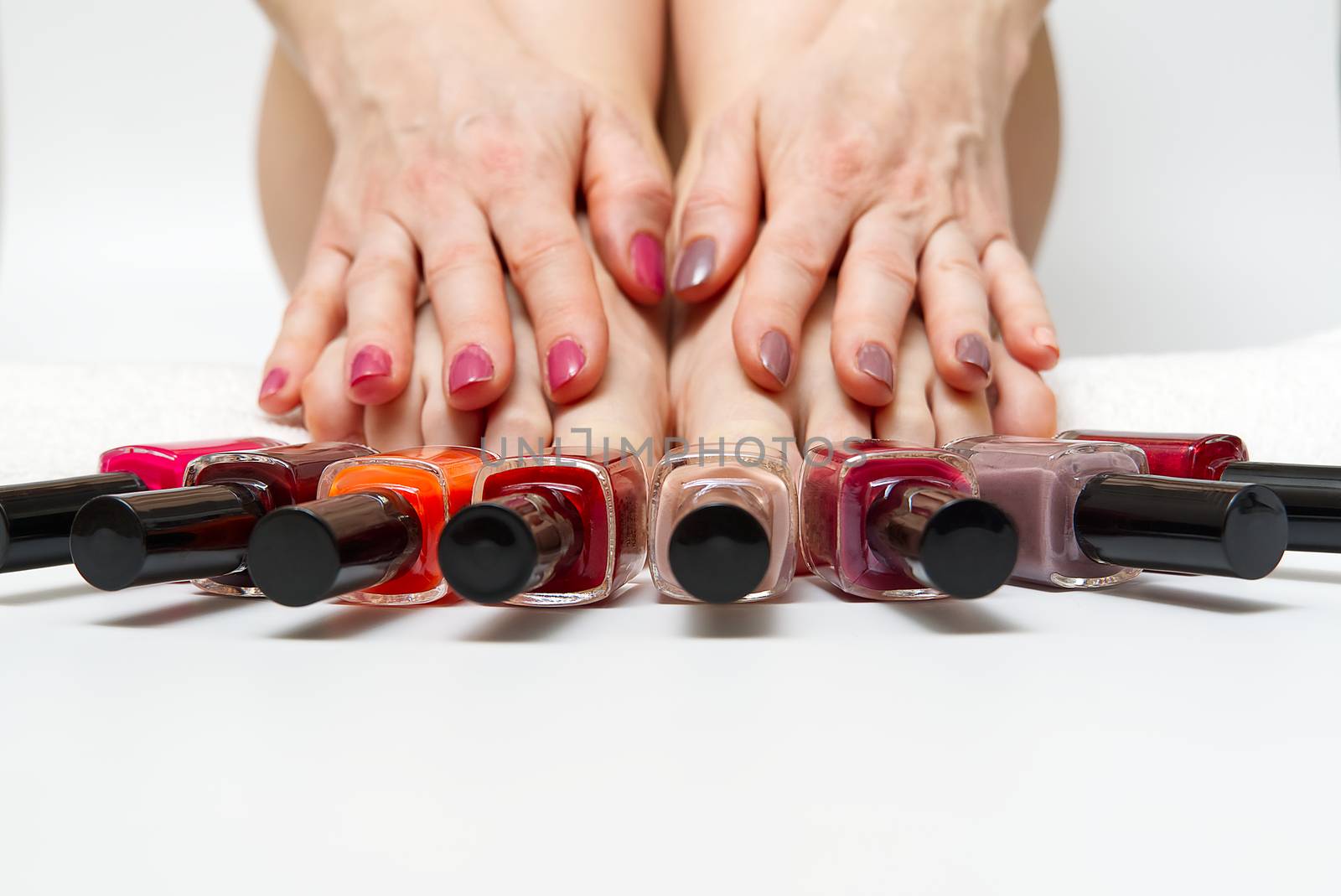 Woman at home spa doing pedicure to herself in white background, close-up. by PhotoTime