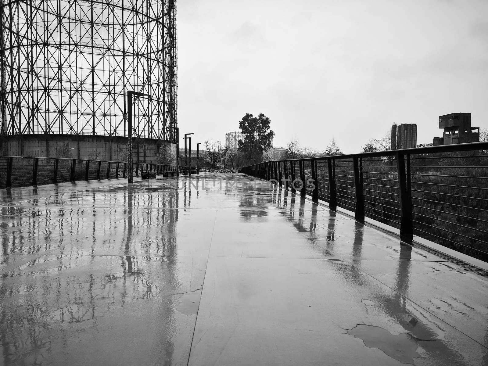 Reflections of an ex industrial gasometer on the street after the rain by cromam70