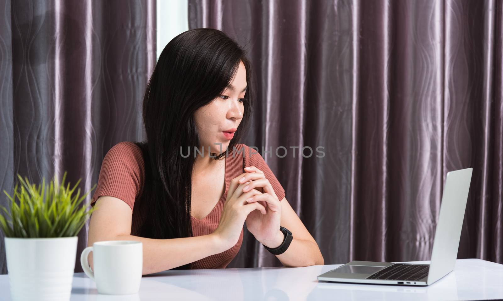 Work from home, Smiling Happy Asian business young beautiful woman sitting on desk workspace video call conferencing by webcam laptop computer technology at home office, Face expression WOW watching
