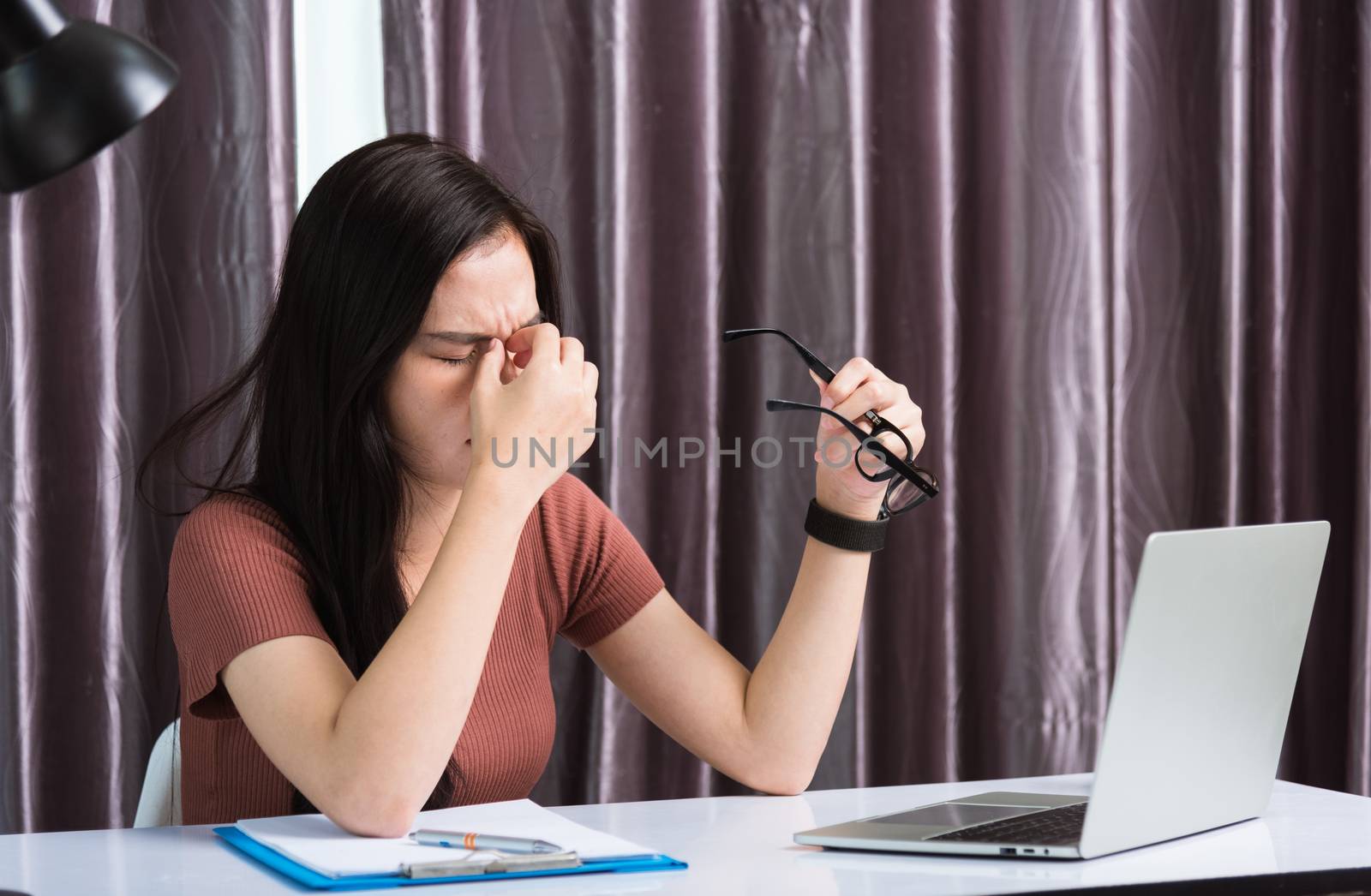 Work from home, Fatigued or strain Asian business young beautiful woman sits on desk workspace feeling tired stressed hold his nose close eyes after see screen long time of laptop computer at office