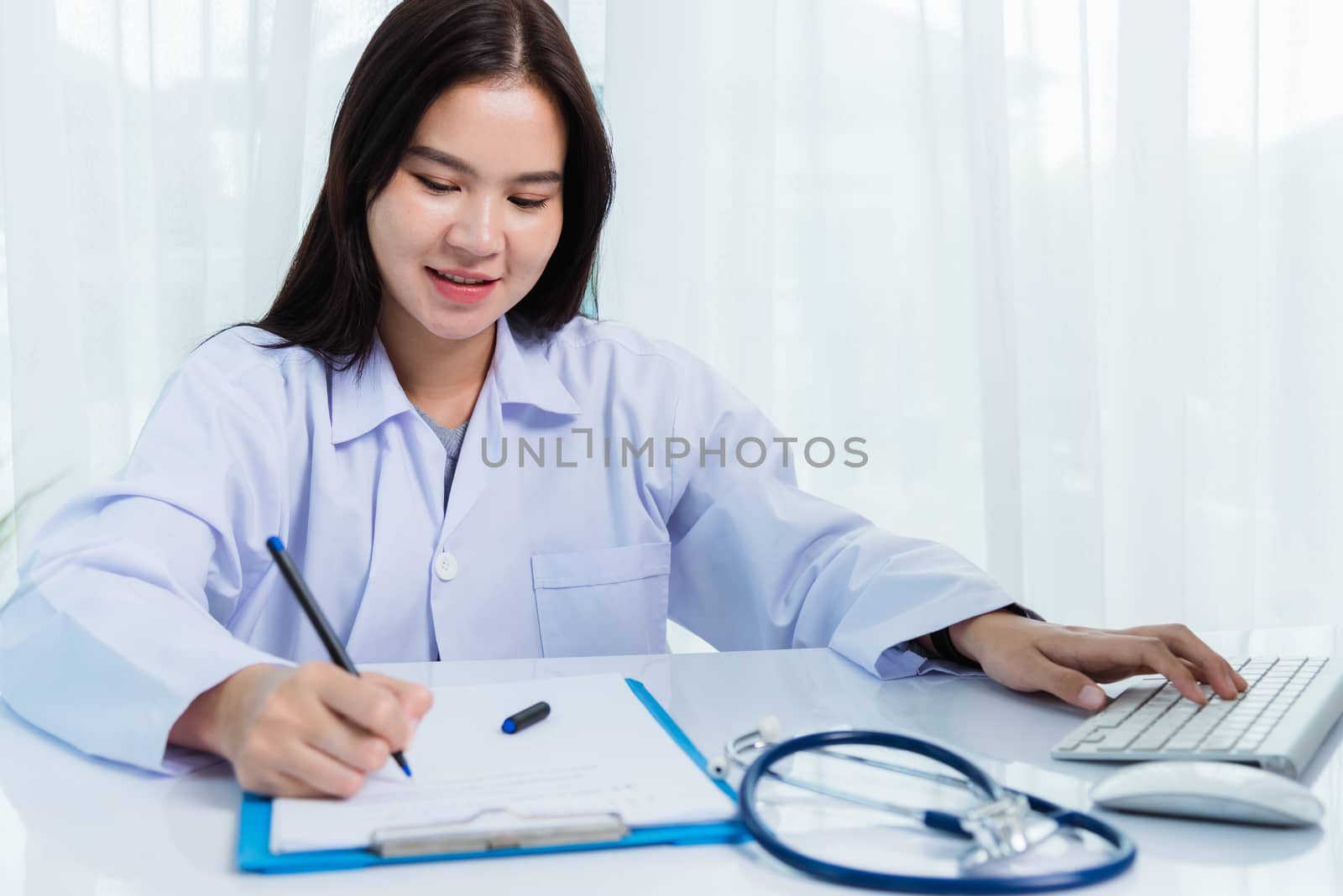 Doctor woman writing something on paperwork or clipboard white p by Sorapop