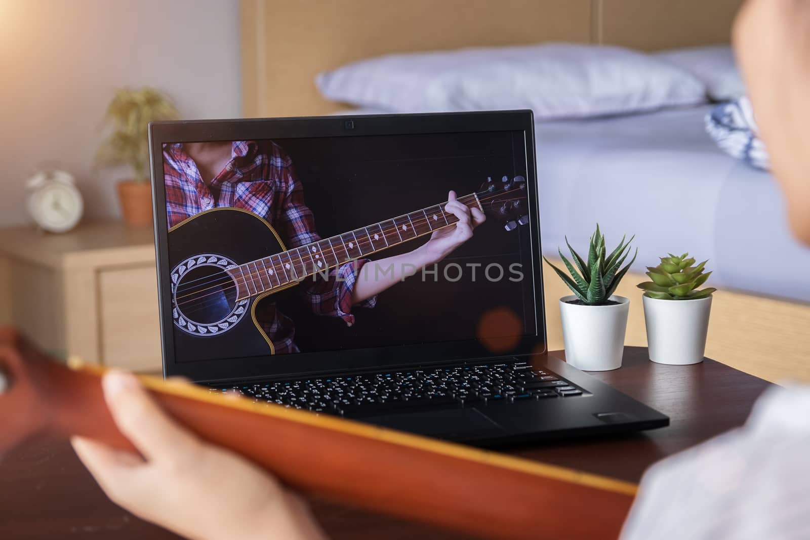 music academy online lesson concept. teenage spend their free time doing interesting activity at home by learning to play guitar chord from website via laptop computer application.