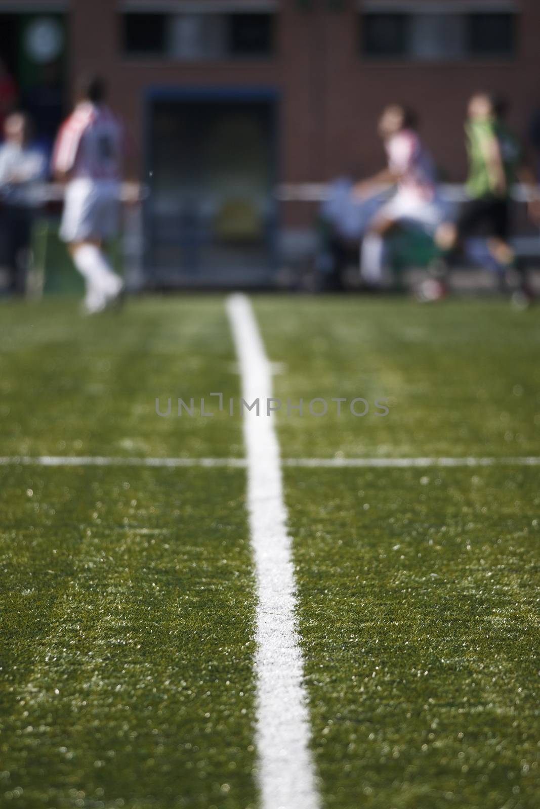 Detail of lines of soccer field with soccer players at background and out of focus.