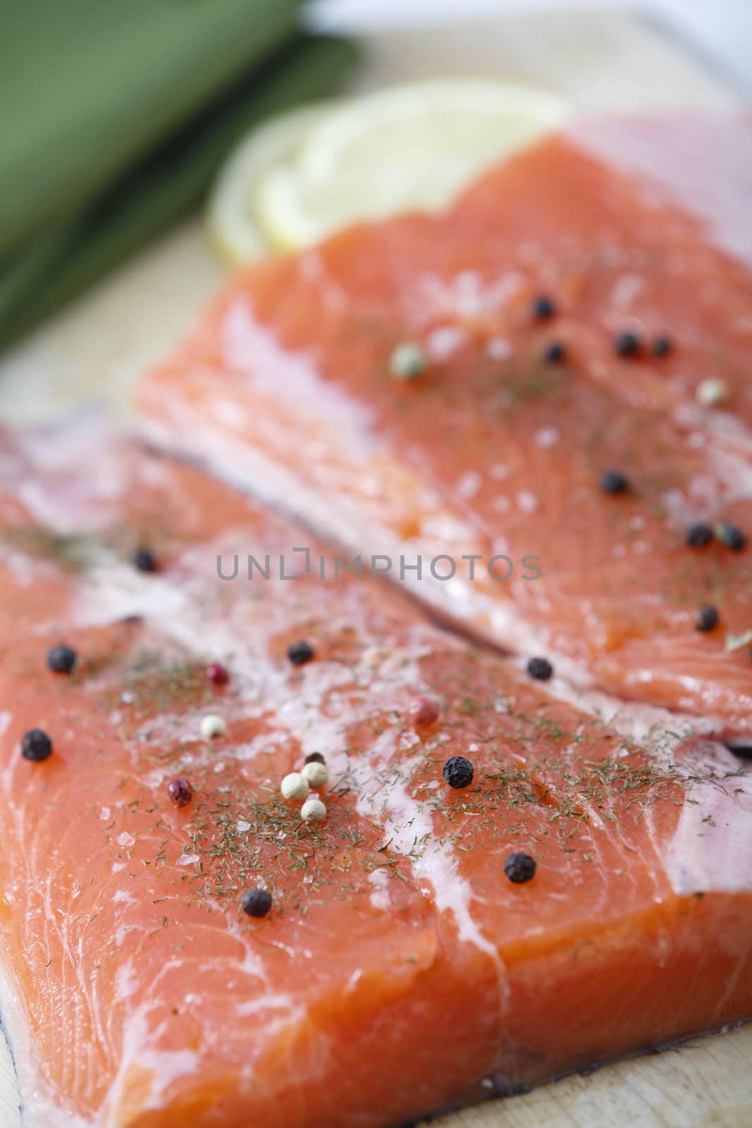 Two raw salmon pieces ready on a chopping board. Focus is on left fillet.