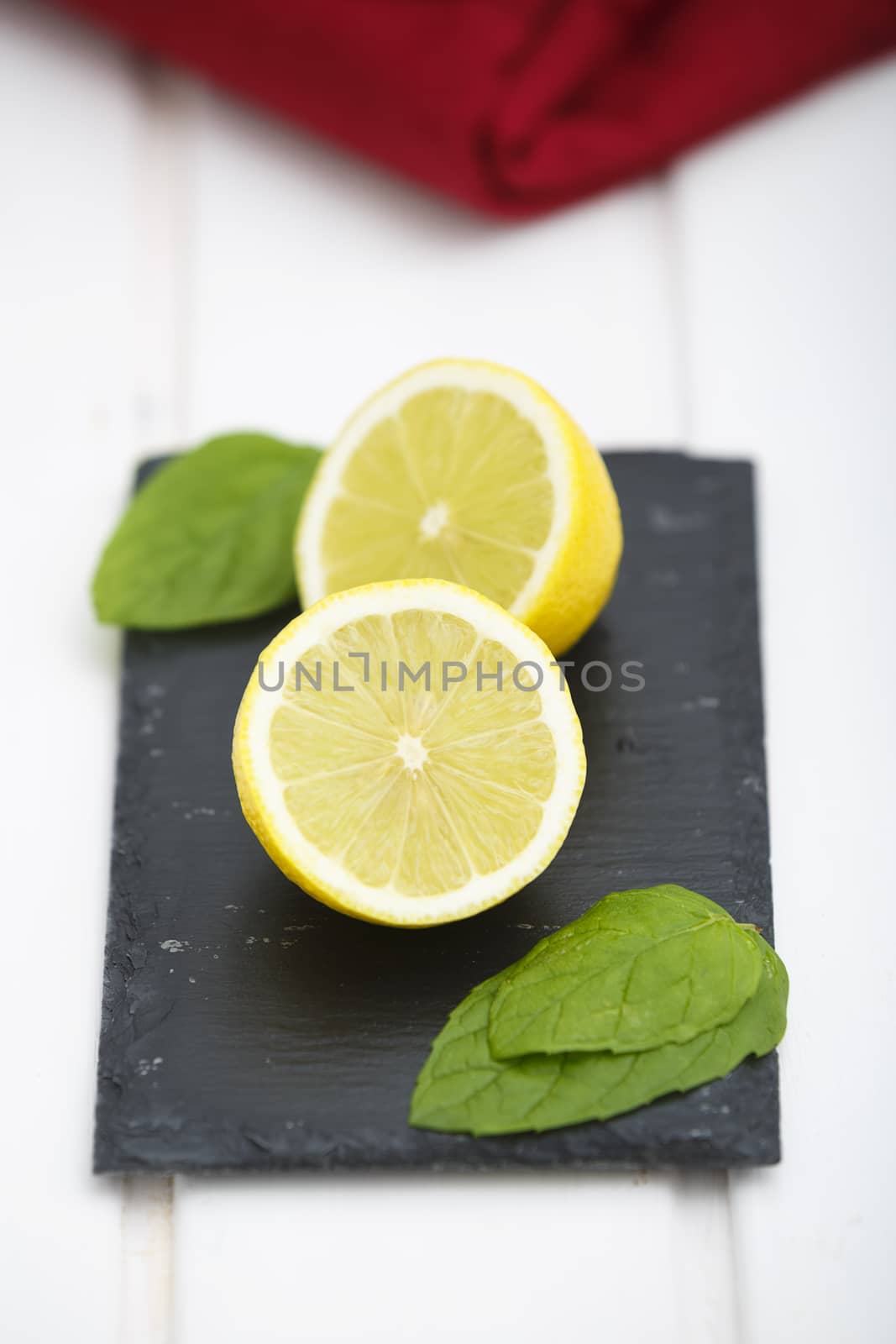 Lemon in halves on a blackboard with green leaves and red napkin.