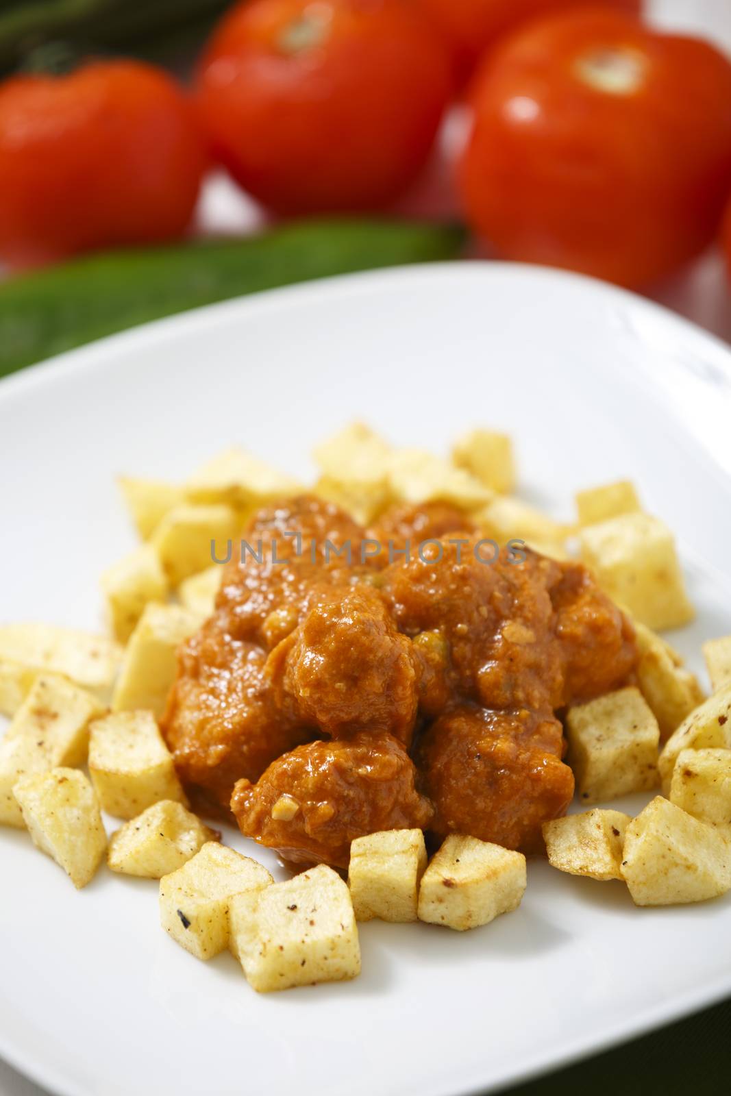 Meatballs with tomato sauce and fries around them.