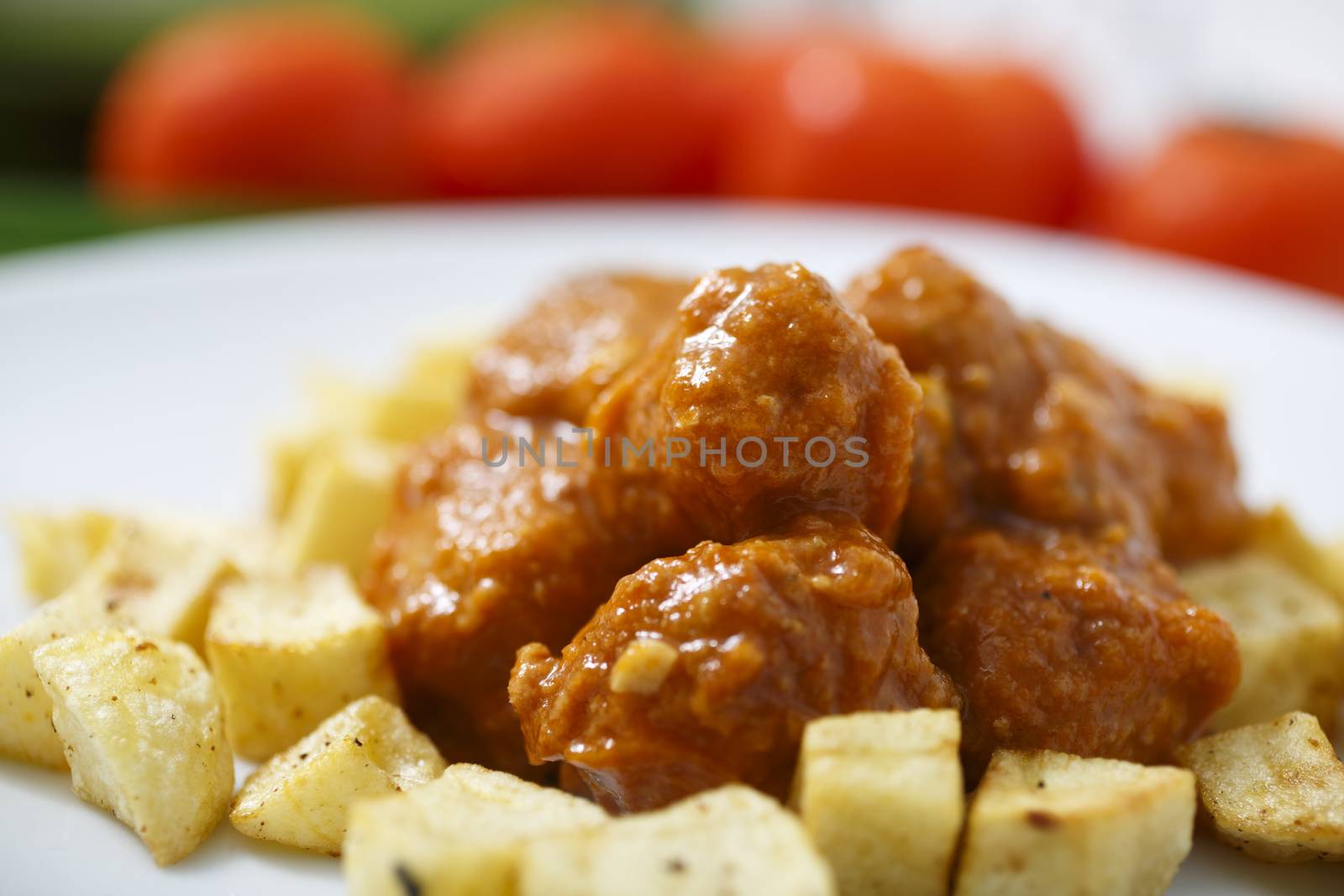 Meatballs with tomato sauce and fries around them.