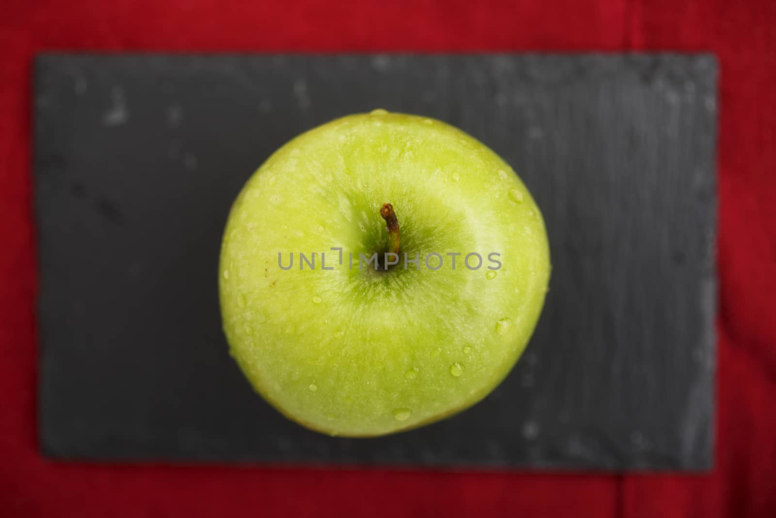Green apple on blackboard on top of red napkin.