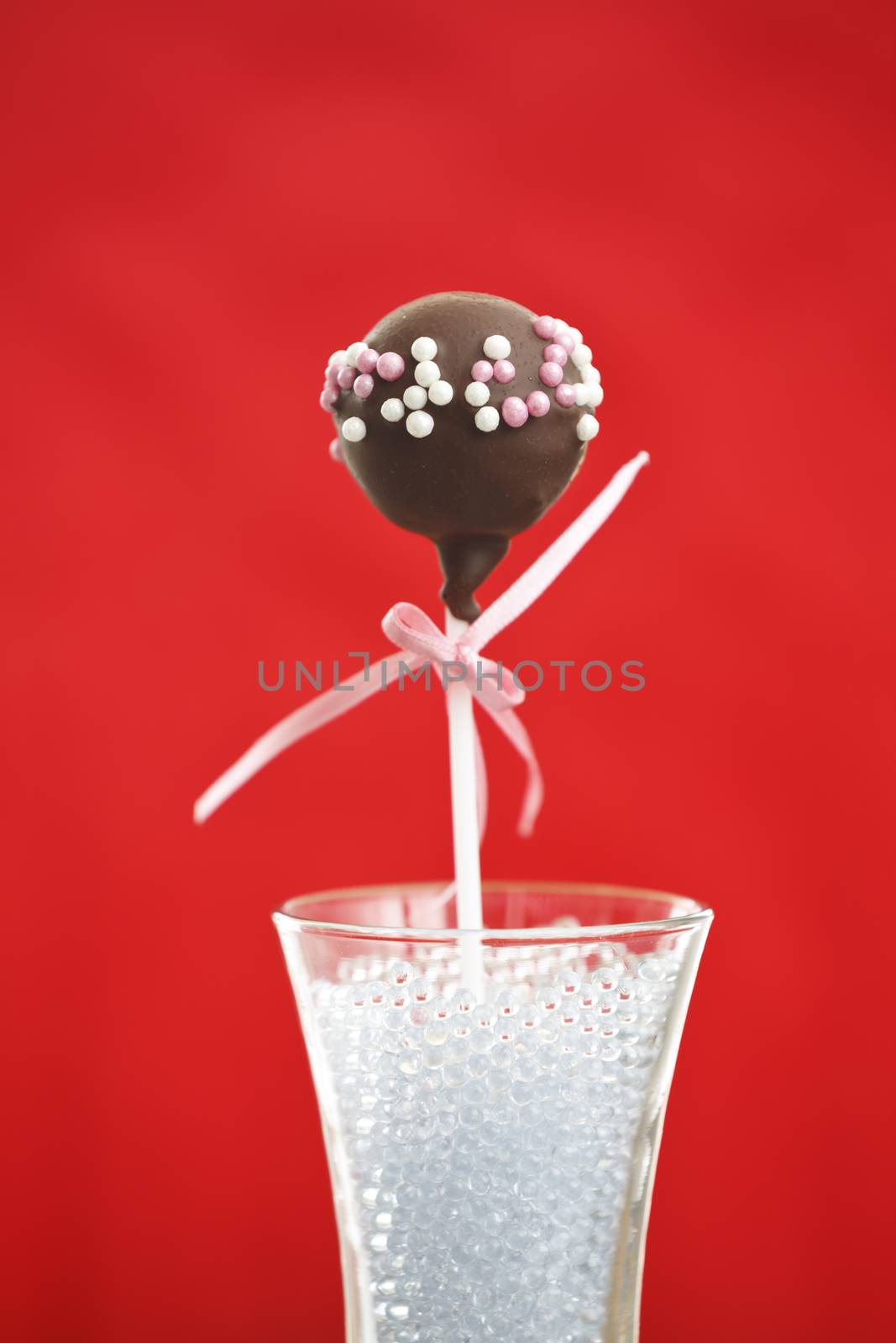 A single cakepop over red background.