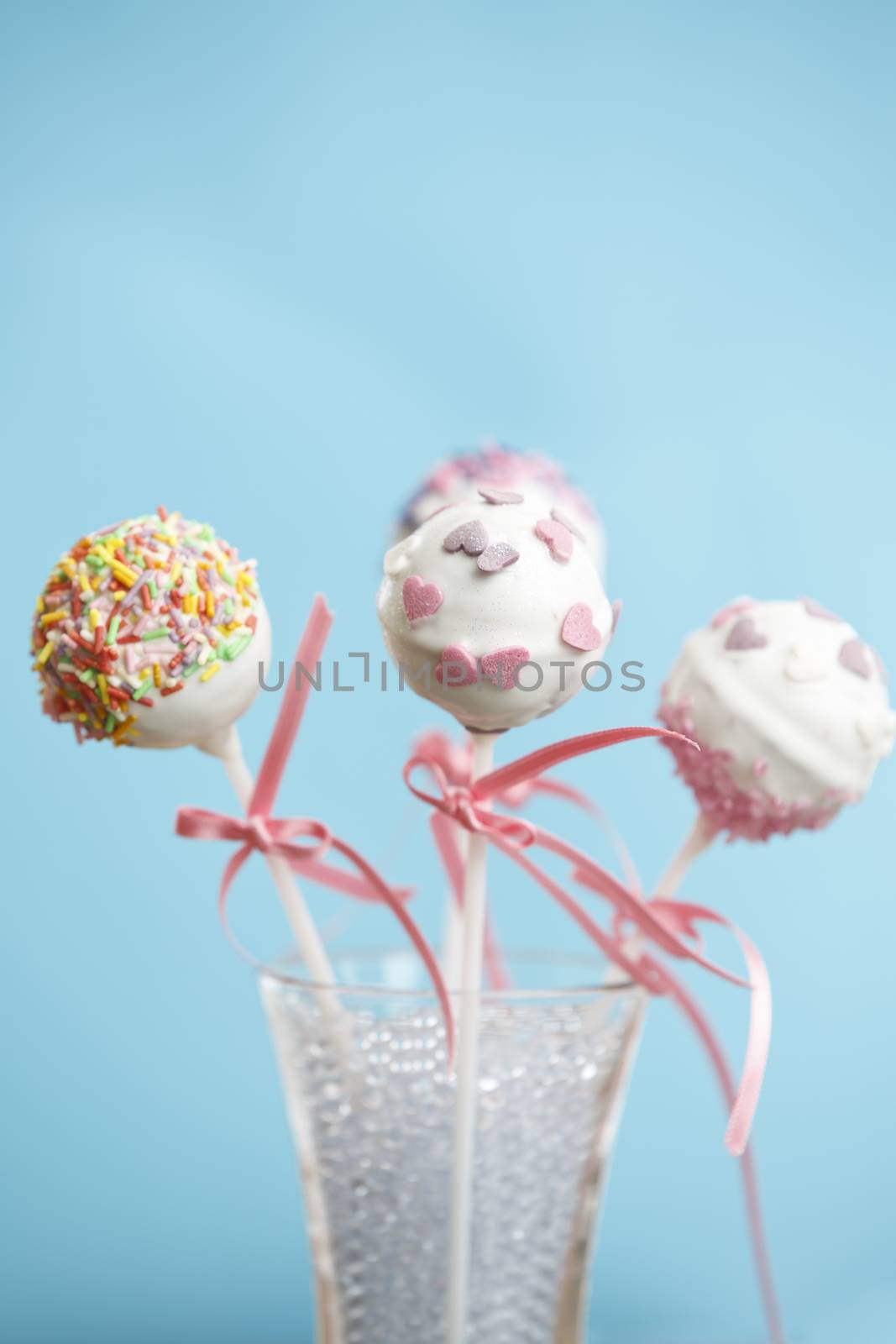 Cakepops over blue background with pink ribbon.