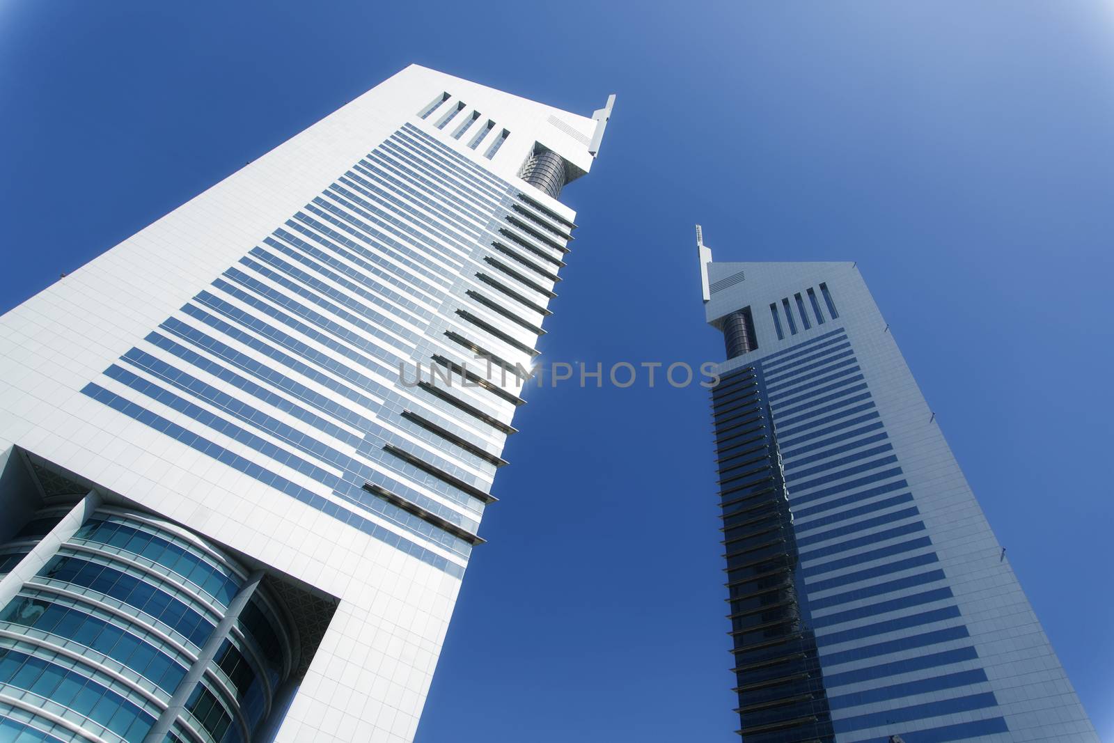 Beautiful mirror buildings, two of them, from a personal perspective. The color of the image is blue, giving to the image a business look. The sky is beauty and clear and there is a shine in one of the buildings