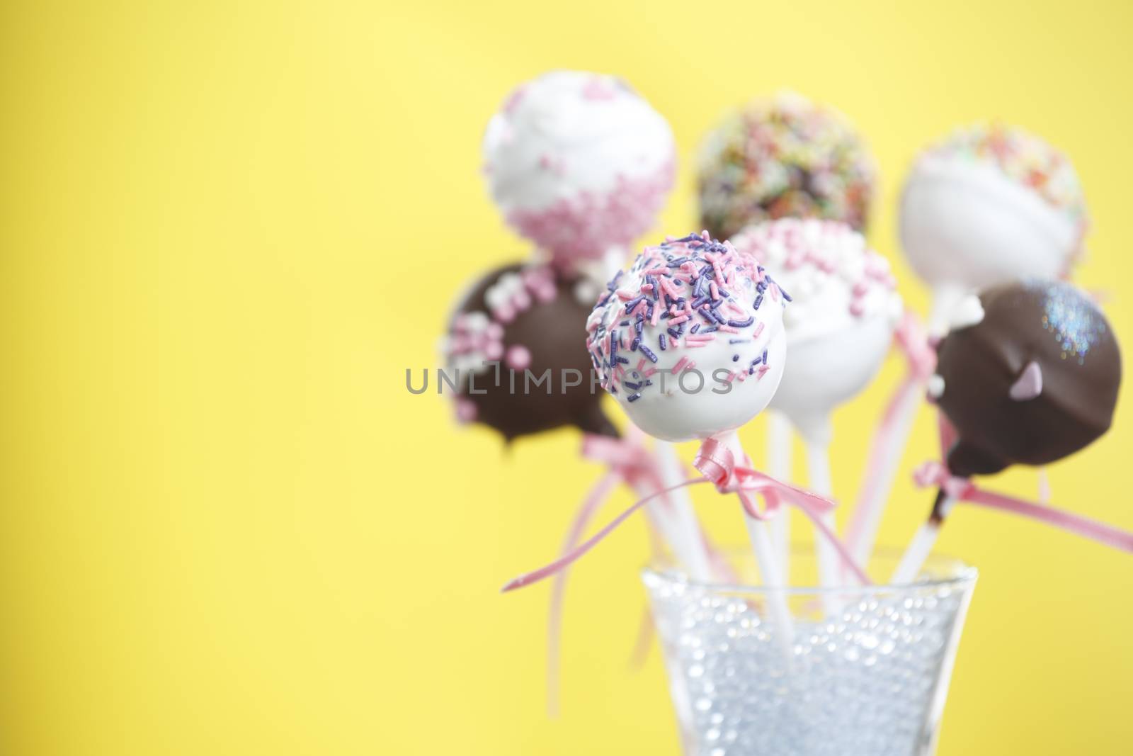 Cakepop over yellow background and space at the left.