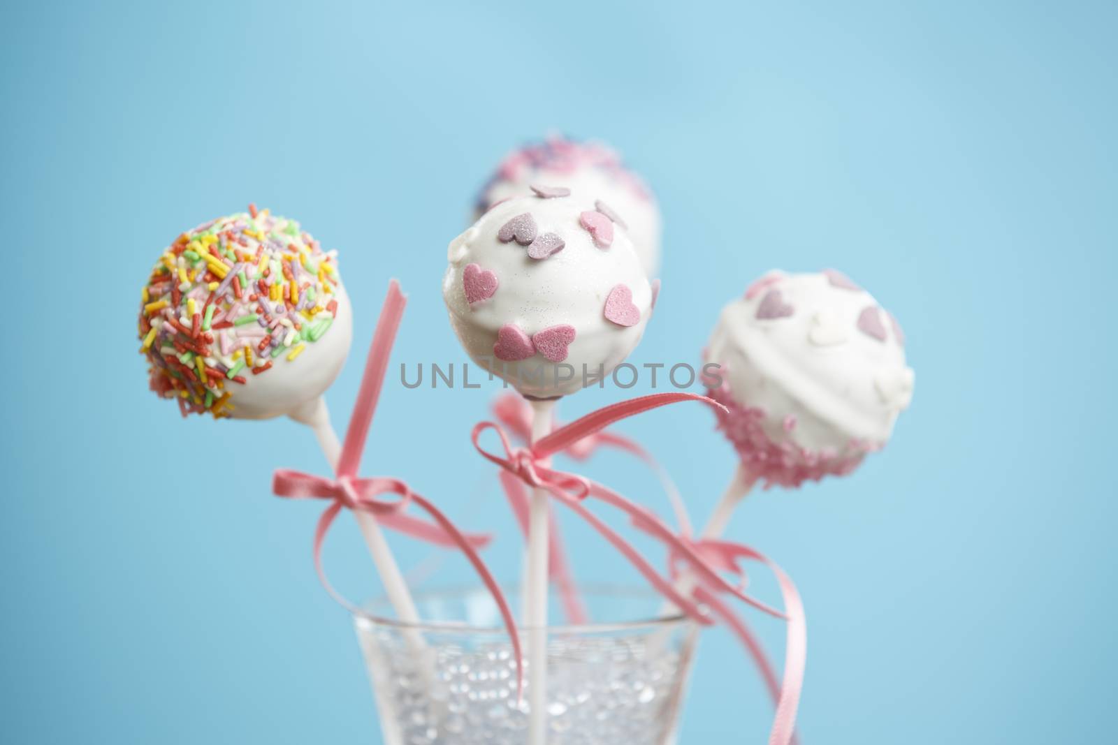 Cakepops over blue background with pink ribbon.