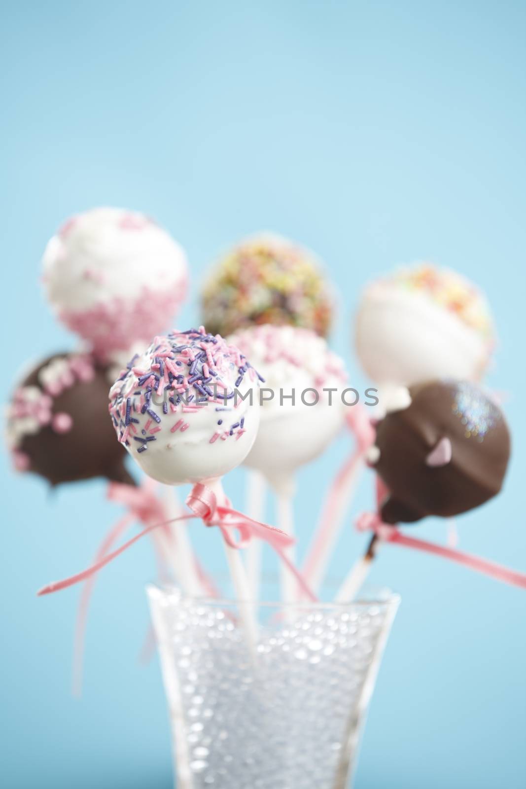 Cakepops over blue background with pink ribbon.