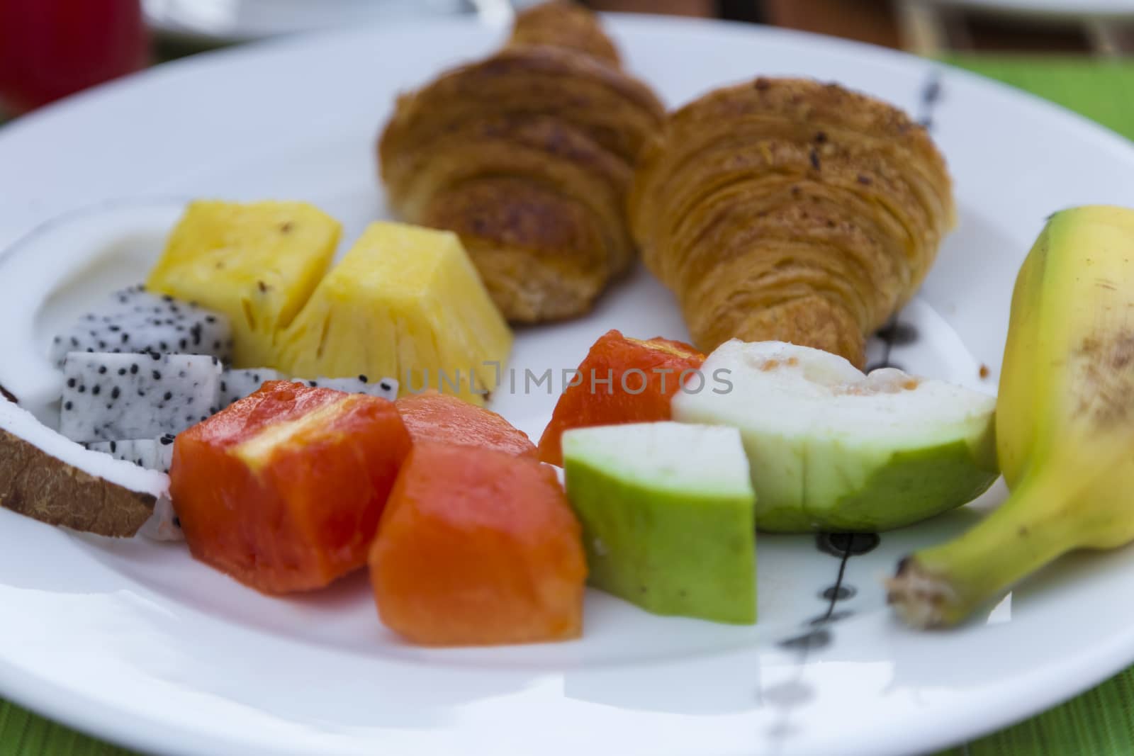 Delicious healthy breaklfast outdoors in a wooden table with sea at background. The breakfast consists of fresh fruit and waffles with pancakes.