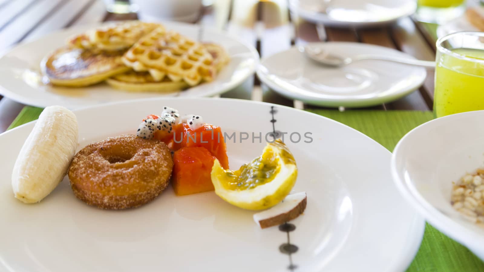 Delicious healthy breaklfast outdoors in a wooden table. The breakfast consists of fresh fruit and waffles with pancakes, also there is a kiwi juice.