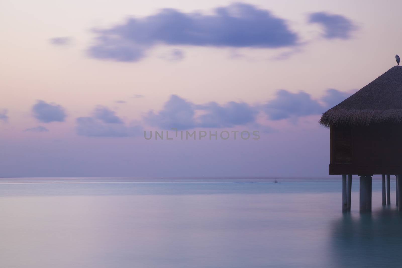 Bungalow over the water at sunset. Long exposure. Tranquil sea.