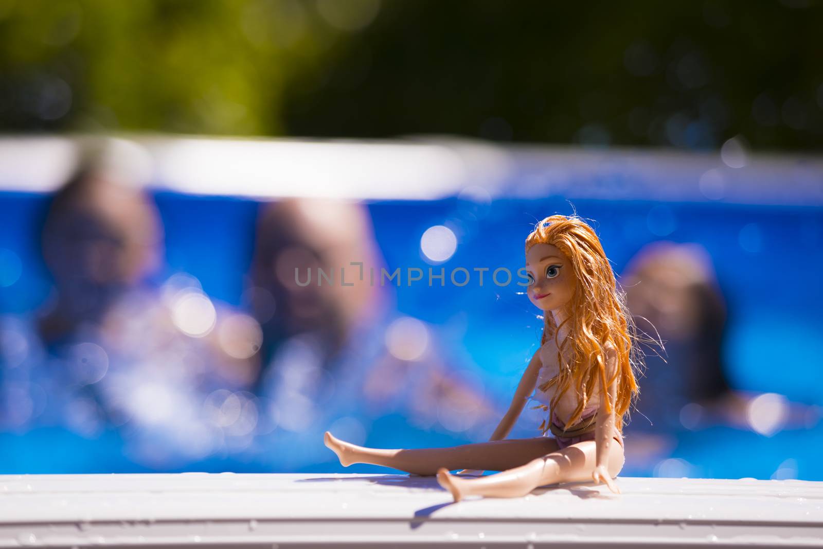 Family having a good time in the swimming pool. The family are out of focus while the doll is on focus.