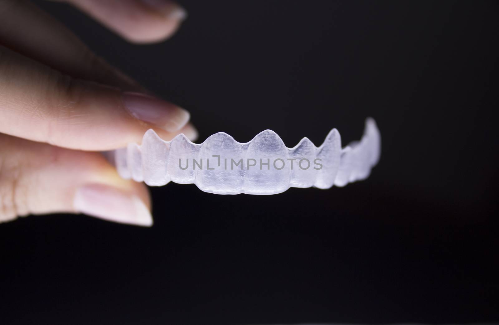Invisible dental orthodontics held by a womans fingers