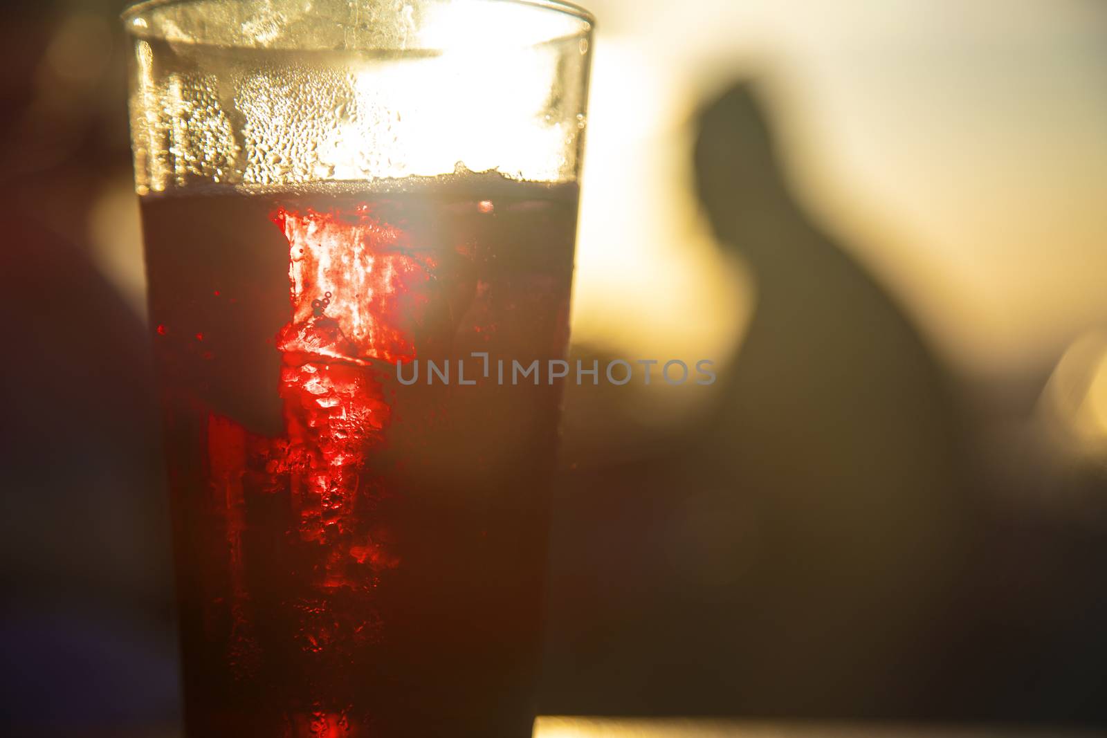 Red wine against the sun with male silhouette at background