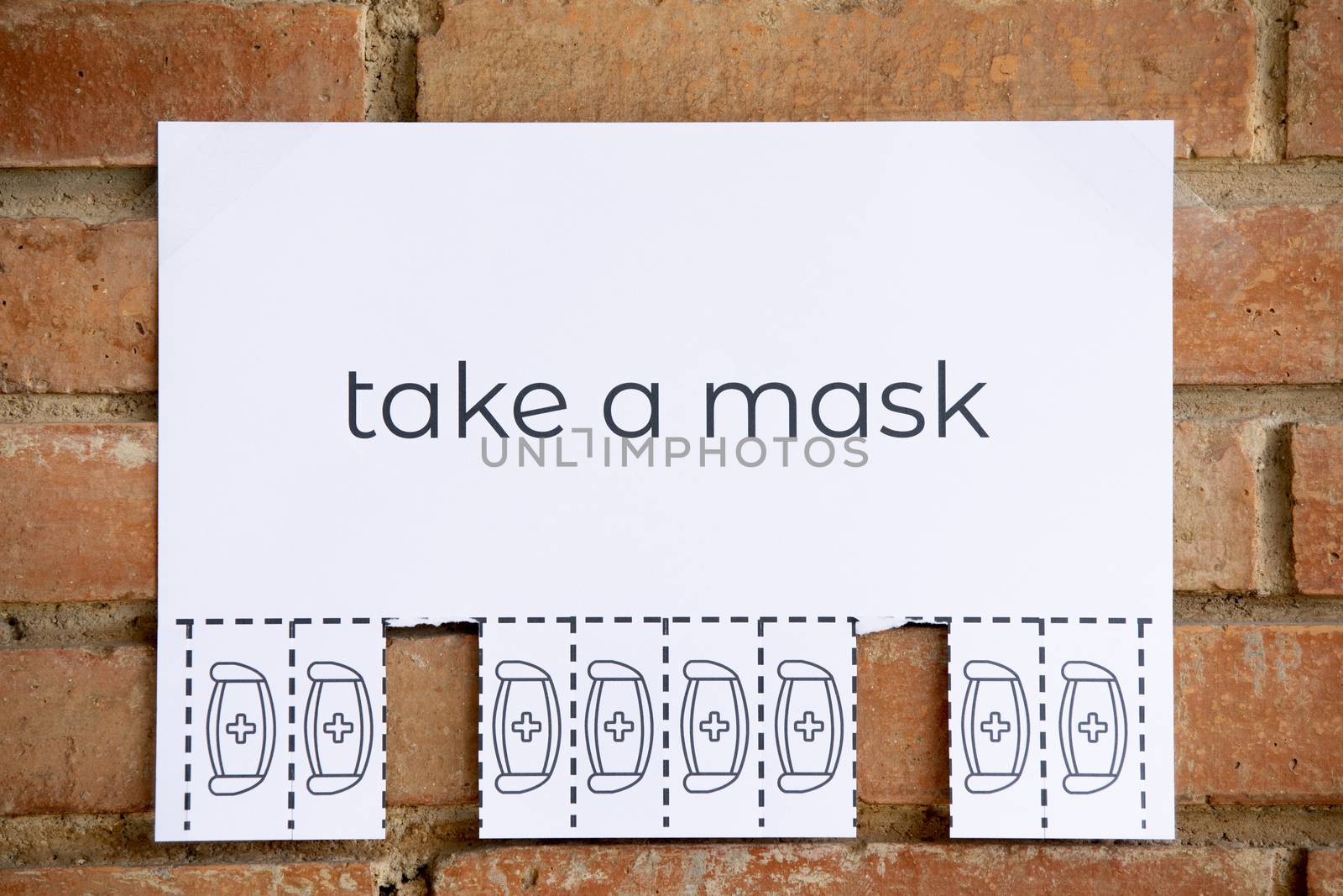 Tear off paper on brick wall with phrase "take a mask". Be responsible on what you do.