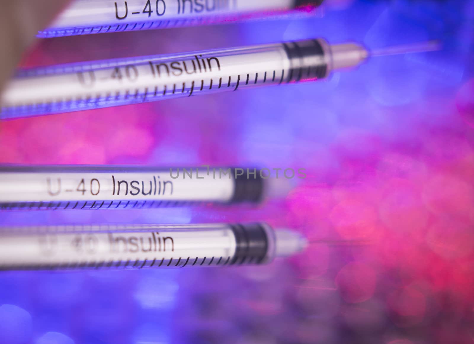 Insulin syringes on multicolored background out of focus