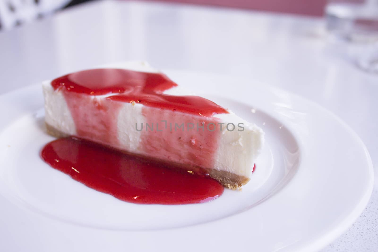 White plate with cheese cake with strawberry syrup