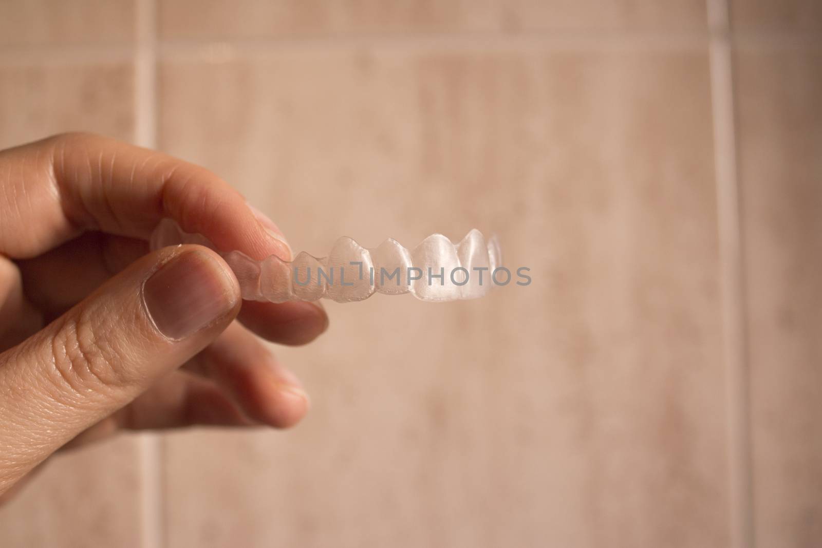 Hand of woman holding invisible dental retainer