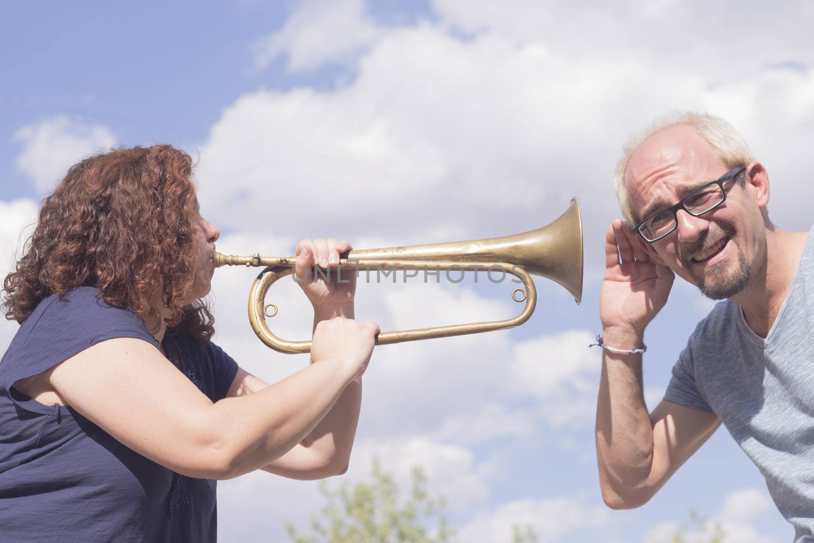 Man and woman playing trumpet on sky background