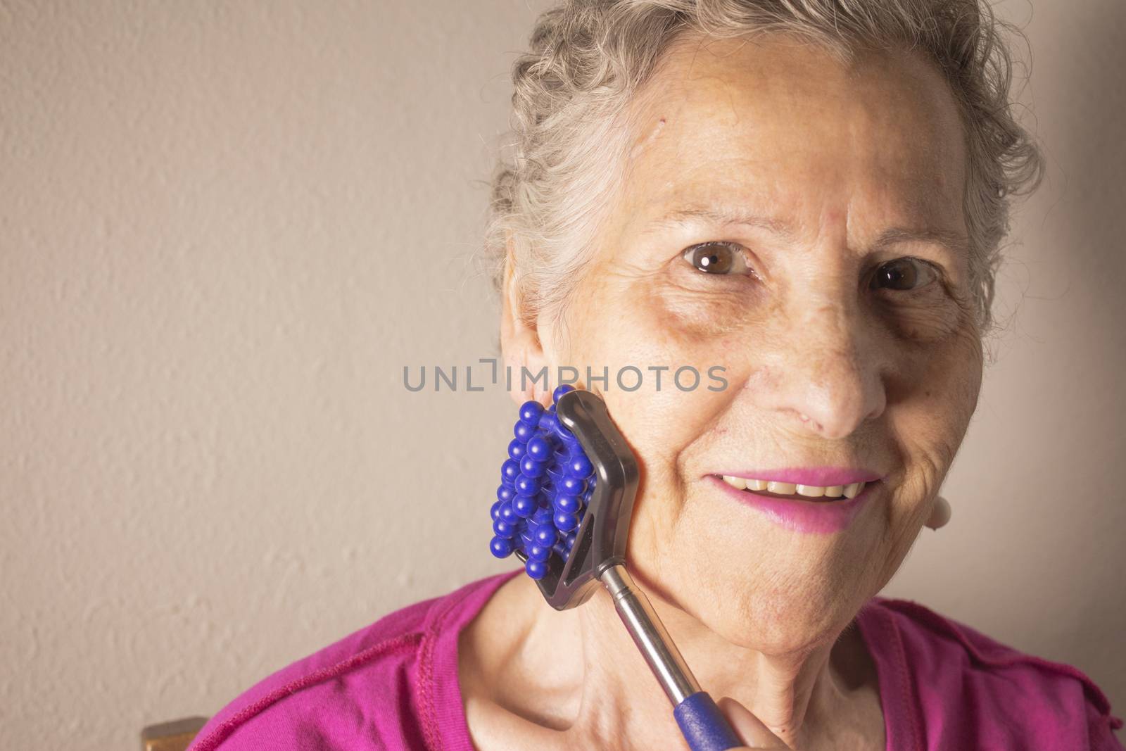 Older woman self massaging with small massager by GemaIbarra