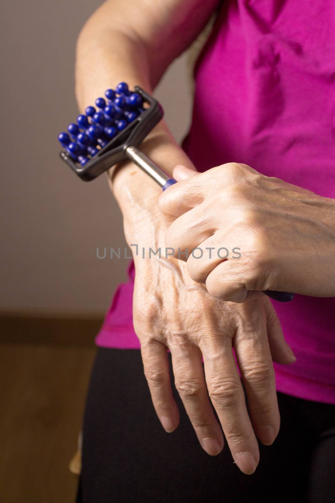 Older woman self massaging with small massager by GemaIbarra