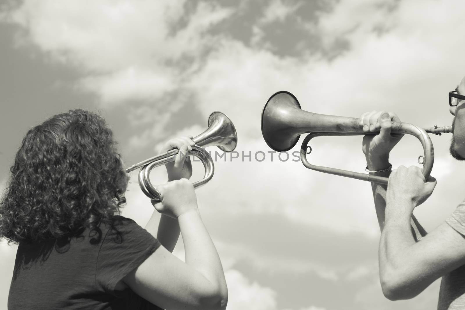 Man and woman playing trumpet on sky background