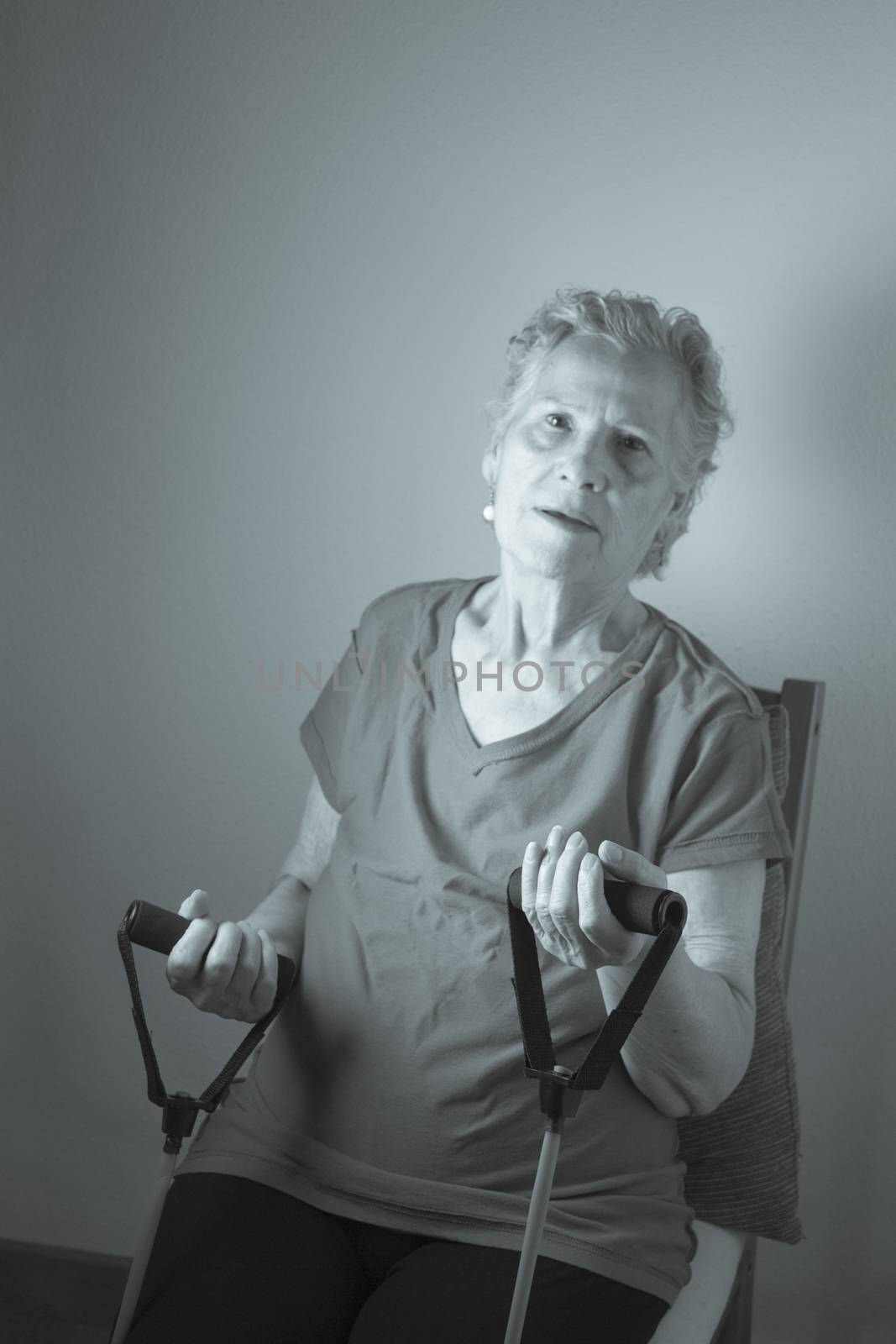 Rehabilitation exercises with elastic resistance rubber for older woman with cerebral stroke